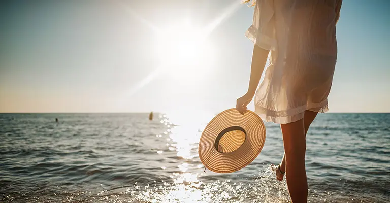 Eine Frau genießt ihren Urlaub am Meer und profitiert von den Reisevorteilen ihrer Kreditkarte