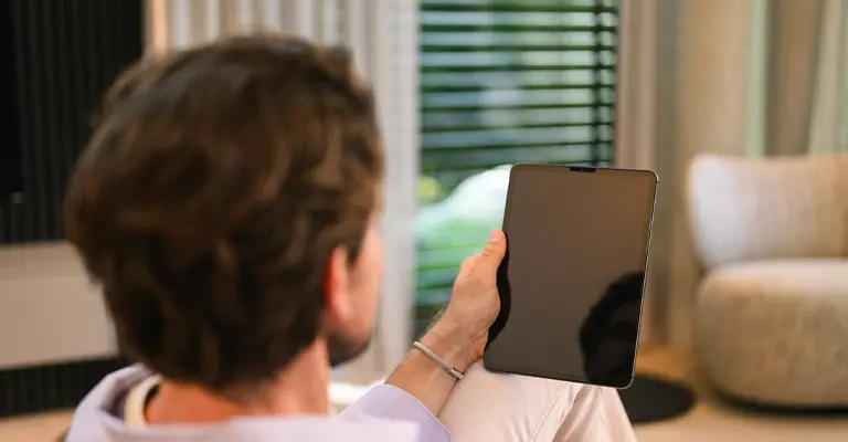 Ein Mann überlegt über sein Tablet den Mercedes Creditcard Newsletter zu abonnieren